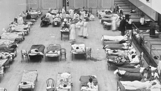 FILE - In this 1918 file photo made available by the Library of Congress, volunteer nurses from the American Red Cross tend to influenza patients in the Oakland Municipal Auditorium, used as a temporary hospital. Science has ticked off some major accomplishments over the last century. The world learned about viruses, cured various diseases, made effective vaccines, developed instant communications and created elaborate public-health networks. Yet in many ways, 2020 is looking like 1918, the year the great influenza pandemic raged. (Edward A. 