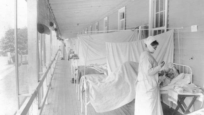 FILE - In this November 1918 photo made available by the Library of Congress, a nurse takes the pulse of a patient in the influenza ward of the Walter Reed hospital in Washington. Science has ticked off some major accomplishments over the last century. The world learned about viruses, cured various diseases, made effective vaccines, developed instant communications and created elaborate public-health networks. Yet in many ways, 2020 is looking like 1918, the year the great influenza pandemic raged. (Harris & Ewing/Library of Congress via AP, File)